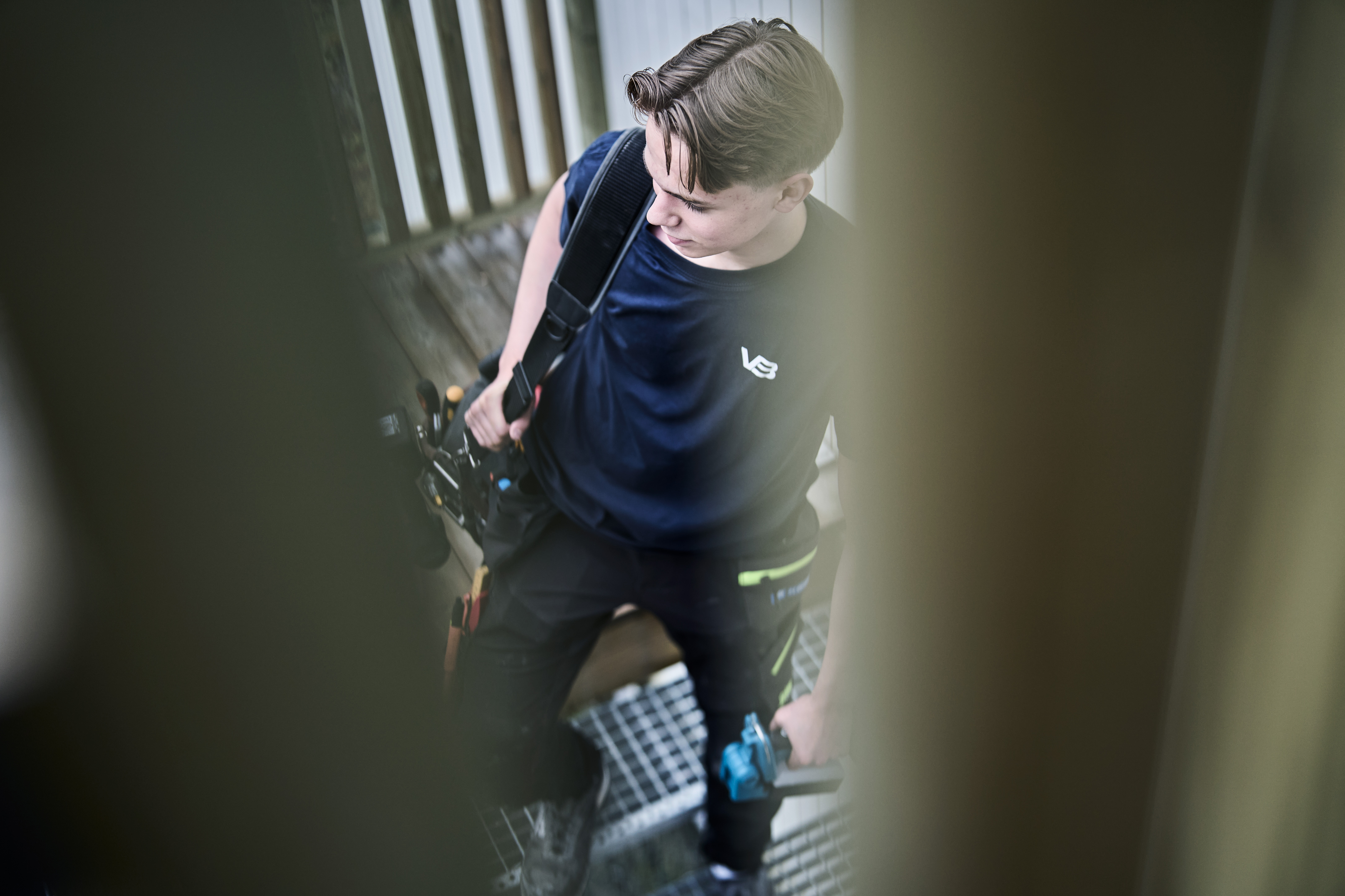 VB-rørlegger med arbeidsveske over skuldra på vei inn til et prosjekt.